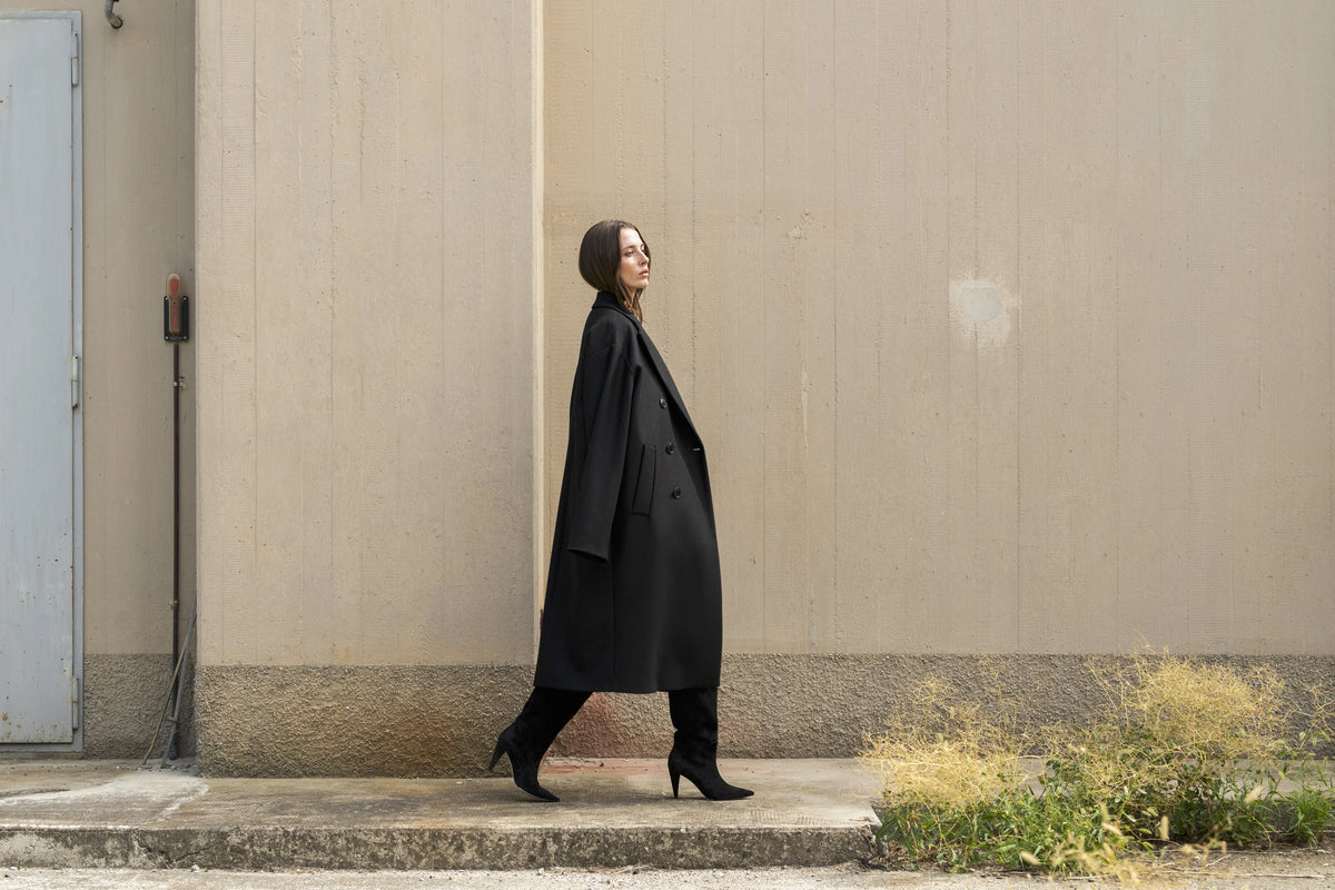 DOUUOD FW26–27, cappotto nero e architettura dai toni naturali